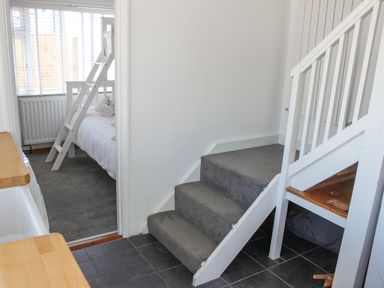 A hallway with carpeted stairs and a view into a bedroom with bunk beds at Rock Point in Salcombe