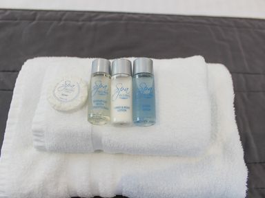 Bottles of spa works shampoo with conditioner hand and body lotion and body wash with a soap on folded white towels
