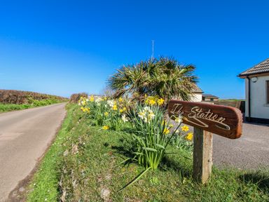 A pathway with flowers and a sign post at The Station in Bolberry