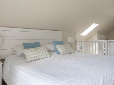A bedroom with a double bed pillows bedside lamp and a skylight window at Stable End Cottage in Malborough