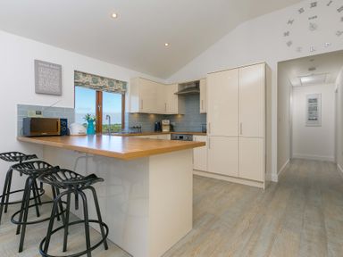 A kitchen with a counter and stools at Mellydonen Beder Del (Melly), Tor Down Quarry St Breward
