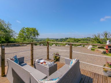An outdoor patio with furniture and a scenic view at Mellydonen Beder Del (Melly), Tor Down Quarry, St Breward