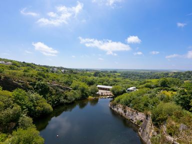 An outdoor view of a lake surrounded by greenery at Mellydonen Beder Del (Melly), Tor Down Quarry in St Breward