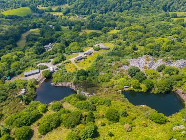 An aerial view of a landscape with trees and a lake at Mellydonen Beder Del (Melly), Tor Down Quarry, St Breward