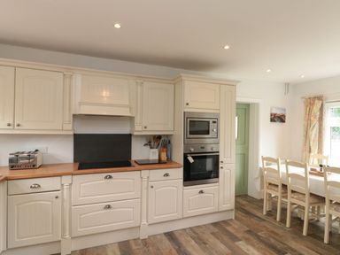 A kitchen with white cabinets built in oven microwave and dining table with chairs at 7 Dale End in Danby near Castleton