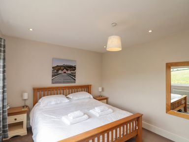 A bedroom with a wooden double bed with white bedding and two nightstands with lamps at 7 Dale End in Danby near Castleton