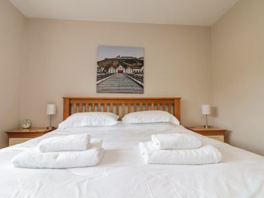 A bedroom with a double bed two bedside tables lamps and towels on the bed at 7 Dale End in Danby near Castleton