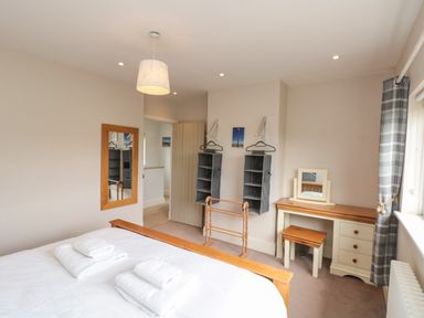 A bedroom with a bed, a mirror on the wall, hanging organizers, a wooden towel rack, and a dressing table with a stool at 7 Dale End in Danby near Castleton