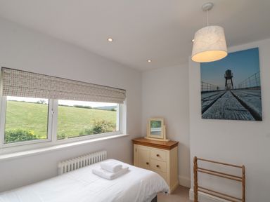 A bedroom with a single bed and white bedding a chest of drawers with a mirror and a wooden towel rack at 7 Dale End in Danby near Castleton