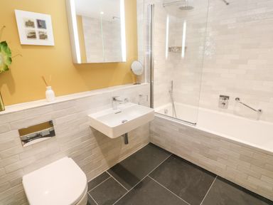 A bathroom with a toilet sink bathtub shower and a yellow wall at Postcard Lodge in Polruan