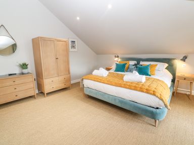 A bedroom with a bed blue bed frame and yellow blanket wooden wardrobe and drawers at Postcard Lodge in Polruan