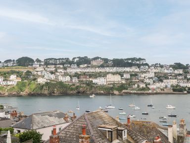 A coastal town with houses on a hillside and boats in the water at Postcard Lodge in Polruan