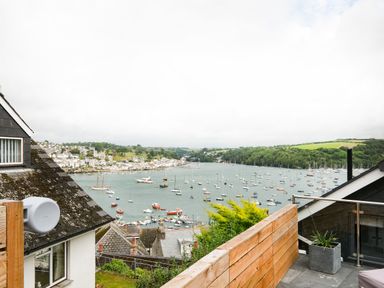 A view of a harbor with numerous boats and houses on hills with greenery at Postcard Lodge in Polruan