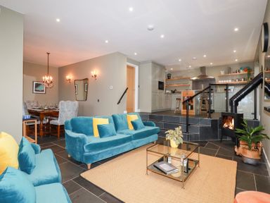 A living room with a sofa, table, and dining area at Postcard Lodge Polruan