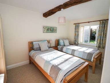 A bedroom with two single beds a bedside table and a window with curtains at The Hideaway in Eckington