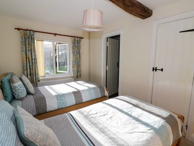 A bedroom with two single beds next to a window with curtains at The Hideaway in Eckington