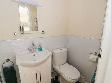 A small bathroom with a white sink cabinet, chrome faucet, mirror, toilet, and towel rings at The Hideaway in Eckington