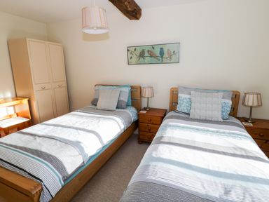 A bedroom with two single beds bedside tables lamps wardrobe and framed picture at The Hideaway in Eckington