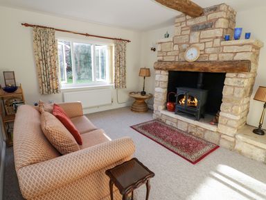 A living room with a sofa a fireplace and a window with curtains at The Hideaway in Eckington