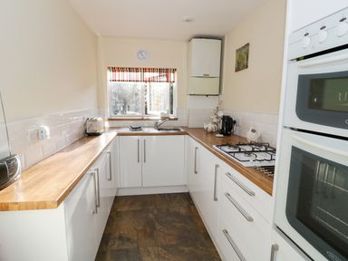 A kitchen with white cabinets wooden countertops a gas stove double oven and a window with a striped blind at The Hideaway in Eckington