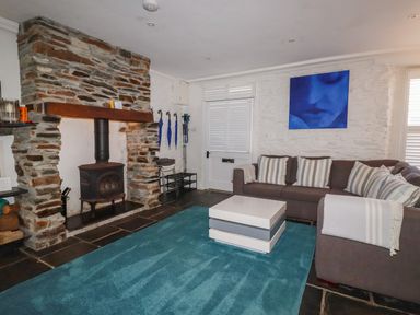A living room with a fireplace and sofa at Rock House in Trebarwith Strand near Tintagel