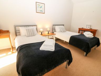 A bedroom with two single beds and bedside table with lamps at Stone Wheel Cottage in Hook Norton