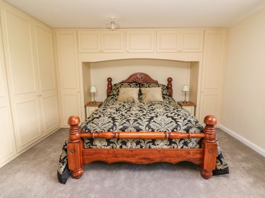 A bedroom with a wooden bed and built in wardrobes at Treboeth in Knighton