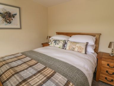 A bedroom with a wooden bed and two bedside tables with lamps at Treboeth in Knighton