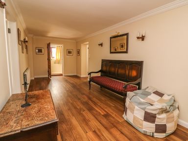 A narrow room with wooden floor a wooden bench a patchwork bean bag and a wooden chest with candle holders at Treboeth in Knighton