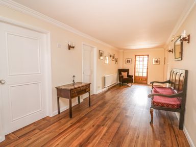 A hallway with wooden floor a wooden table armchair and a wooden bench at Treboeth in Knighton