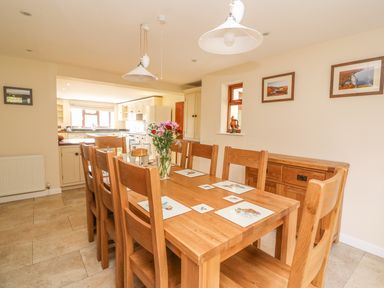 A dining room with a wooden table and six chairs with placemats and flowers on the table at Treboeth in Knighton