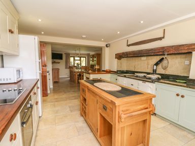 A kitchen with wooden island and dining table in the background at Treboeth in Knighton