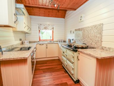 A kitchen with white cabinets wooden ceiling wooden floor and a stove at Pines Pitch in Knighton