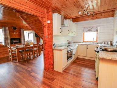A kitchen with white cabinets and granite countertops next to a dining area with a wooden table and chairs at Pines Pitch in Knighton