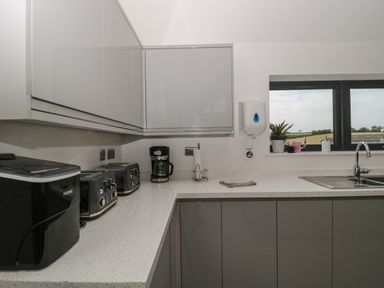 A kitchen counter with appliances including a coffee maker and toasters and a window with a view of fields at Longmynd in Gloucester