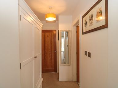 A hallway with a white wardrobe a mirror on the wall wooden doors and framed pictures at Longmynd in Gloucester