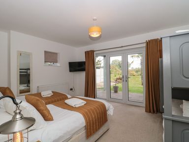 A bedroom with two beds a bunk bed a television and glass doors leading to a garden at Longmynd in Gloucester