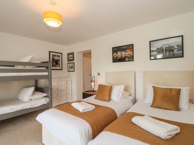 A bedroom with two single beds and a bunk bed with pictures on walls at Longmynd in Gloucester
