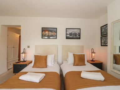 A bedroom with two single beds each with a white towel on a brown bedspread at Longmynd in Gloucester