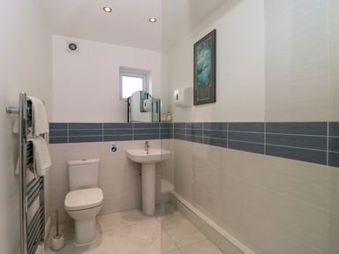A bathroom with a toilet a pedestal sink a towel rack with towels and a mirror above the sink at Longmynd in Gloucester