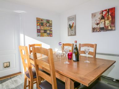 A dining room with a wooden table and chairs with wine and glasses at Bayview in Mevagissey
