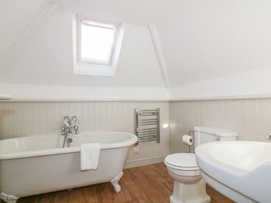 A bathroom with a bathtub a toilet a sink a towel rail and a skylight at Bayview in Mevagissey