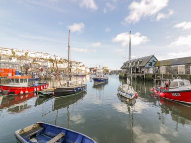 A harbor with boats docked near buildings and houses on a hill at Bayview in Mevagissey