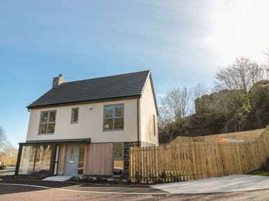 A two story house with a pitched roof and a wooden fence in a suburban area at High Tide House in Craster
