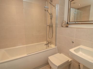 A bathroom with a bathtub shower combination toilet and sink at High Tide House in Craster