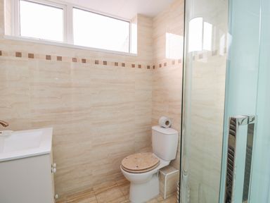 A bathroom with a toilet a sink with cabinet and a glass shower at Beach Cove View in Newbiggin-by-the-Sea