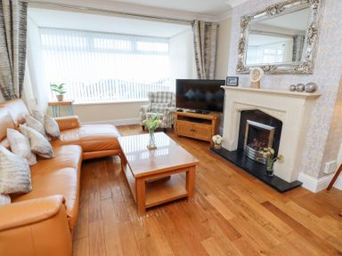 A living room with a sofa, coffee table, and television at Beach Cove View, Newbiggin-by-the-Sea