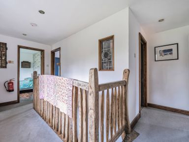 A hallway with a staircase railing and doors at Spring Park Farmhouse in Launceston