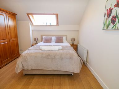 A bedroom with a double bed two bedside tables lamps and a wooden wardrobe at Llain Haf in Llangefni