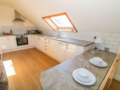 A kitchen with white cabinets a countertop dining area and a skylight window at Llain Haf in Llangefni